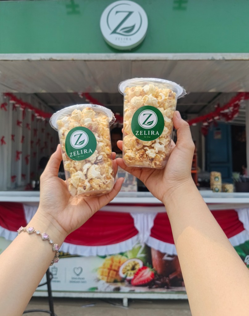 Pelanggan memegang popcorn Zelira di depan booth